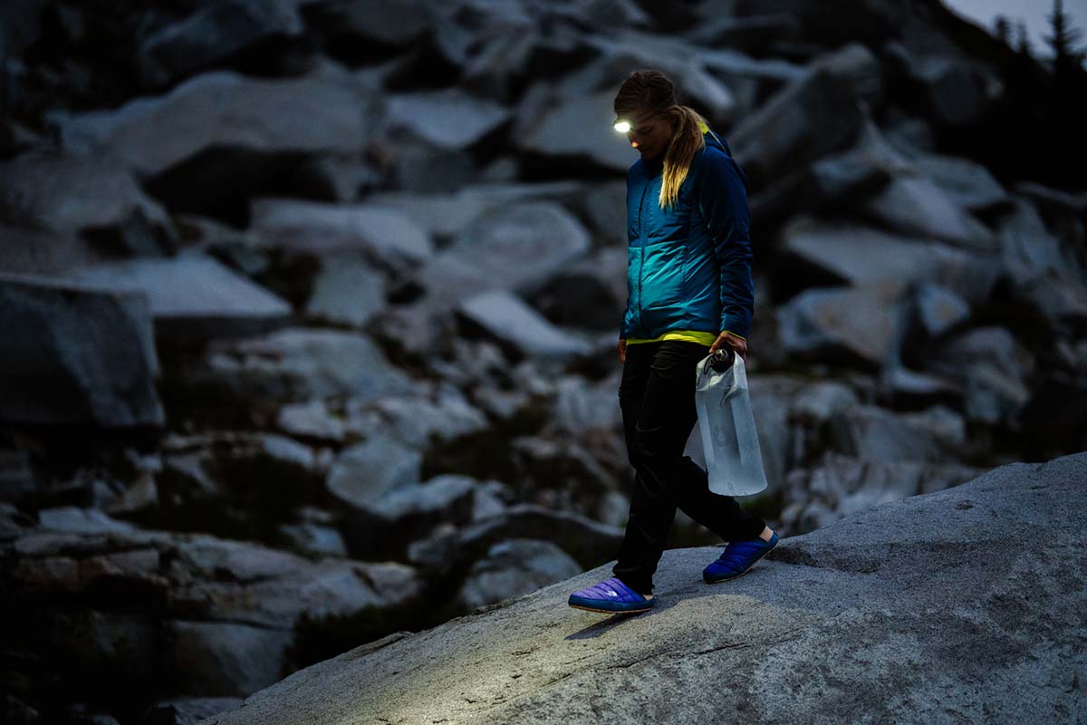 A woman walking at night with water filters while wearing a headlamp