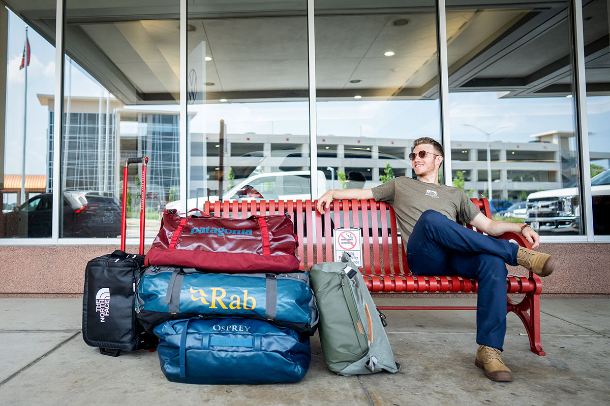 Sitting on bench at airport with group of duffel bags